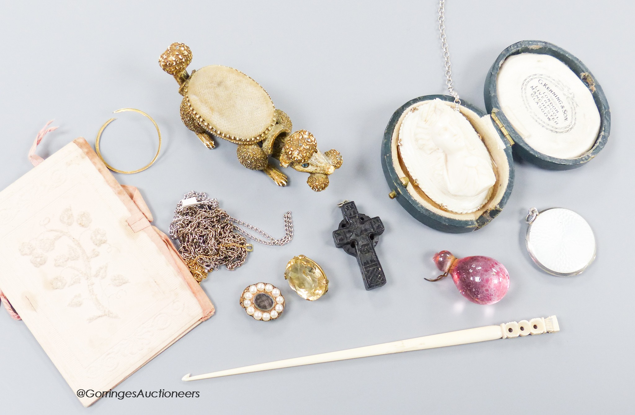 A small group of assorted bijouterie including base metal and composite poodle pin cushion, a white metal and enamel locket on sterling chain, a citrine brooch(lacking pin), a slit pearl set yellow metal mourning clasp e